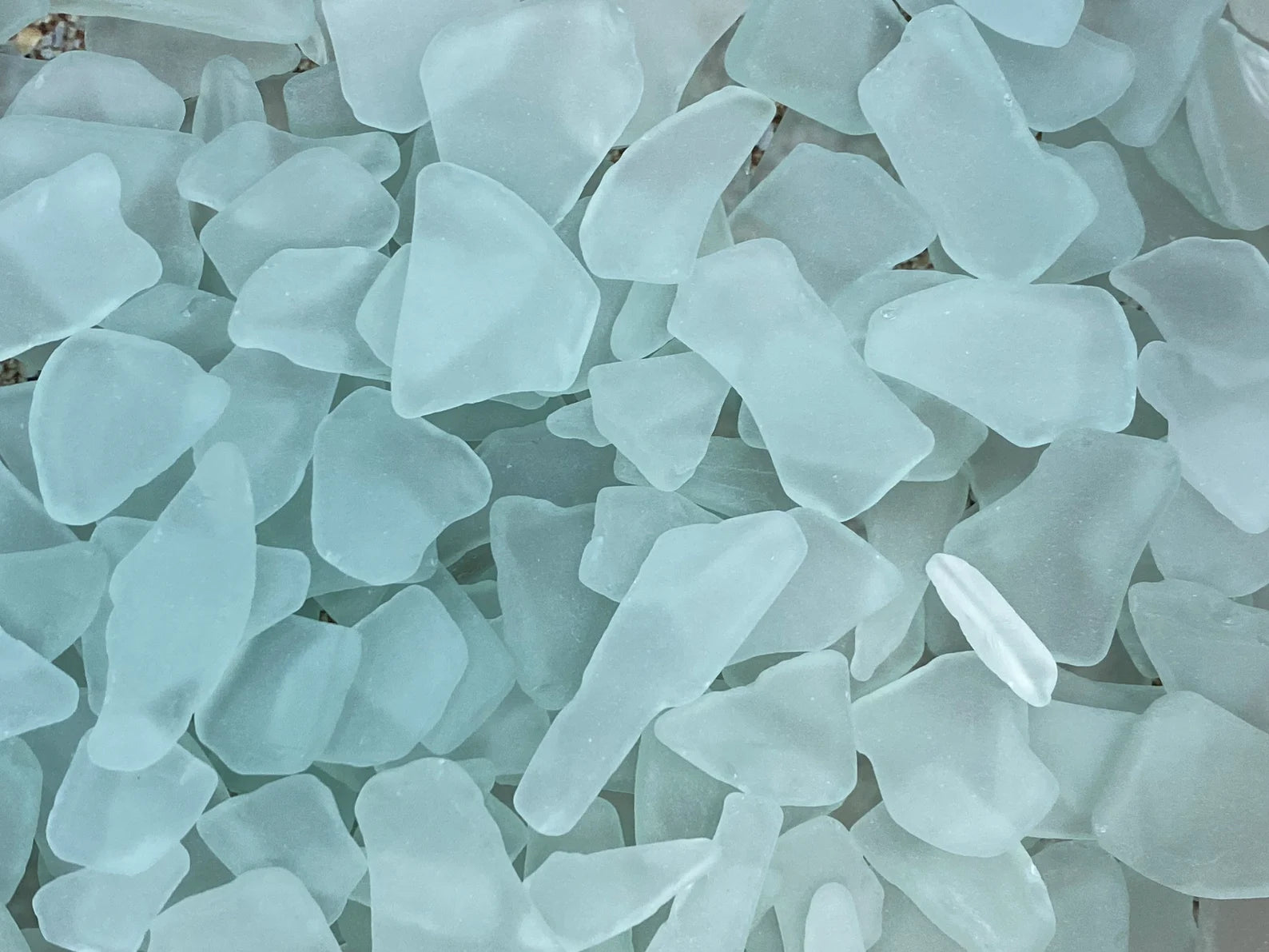 Collection of light blue sea glass pieces on a white background