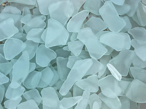 Collection of light blue sea glass pieces on a white background